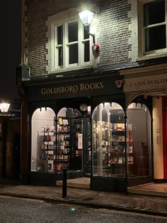 the storefront of goldsbrok books is lit up at night with its lights on