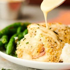 someone is drizzling sauce on some food in a white bowl with green beans