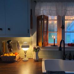 a kitchen sink sitting under a window next to a counter top with lights on it