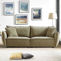 a living room scene with focus on the couch and pillows in the foreground as well as pictures on the wall