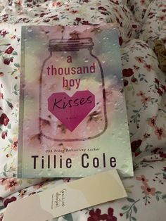 a book sitting on top of a bed next to a tag that says a thousand boy kisses