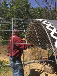 a man standing in front of a metal cage holding a large object up to it's side