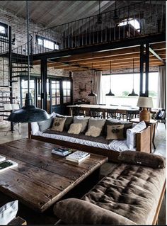 a living room filled with lots of furniture next to a brick wall and ceiling covered in windows