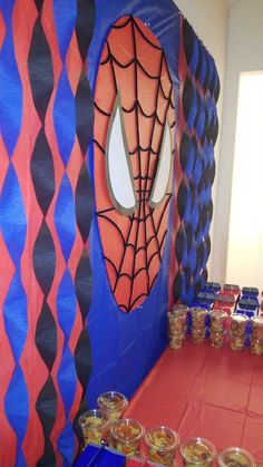 there is a spiderman themed party with drinks on the table and cups in front of it