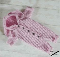 a pink knitted sweater with buttons on the front and bottom, sitting on a white wood floor