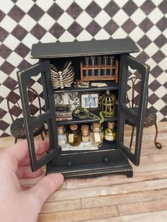 a hand is holding an open miniature cabinet