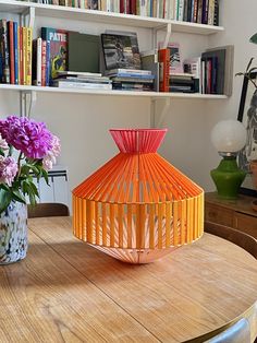 a table with two vases filled with flowers on it and bookshelves in the background