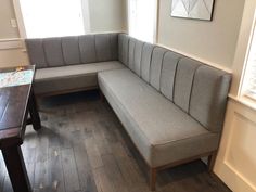 a corner couch sitting on top of a hard wood floor next to a wooden table