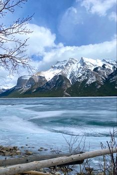 a large body of water with mountains in the background and snow on the ground around it