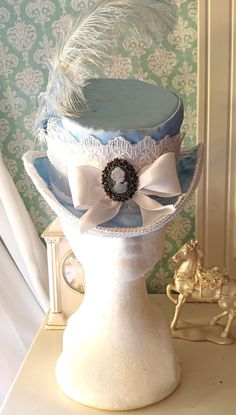 "Victorian/ Bustle Era Small Ladies Top Hat in Sky Blue satin w/ baby blue & white Ostrich Plumes. Partly inspired by the the character, Mina Harker (played by Winona Ryder) in 1992 Film and Academy Award Best Costume Design winner, \"Brahm Stoker's Dracula\" and the 2022 TV Series, \"Billy The Kid,\" this hat is 12 inches from front to back, 9.5 inches wide and has a small (but flexible) 6 inch crown diameter. Centered in the front is a Victorian Style Cameo Brooch with charcoal gray Swarovski Mina Harker, Victorian Bustle, Best Costume Design, Billy The Kid, Bridal Fascinator, Mini Top Hat, Tea Party Hats, Victorian Wedding, Small Lady