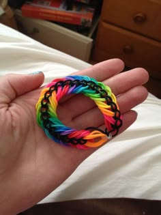 a person holding a rainbow colored bracelet in their hand