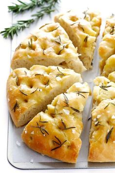 several pieces of bread on a tray with some rosemary sprigs next to it