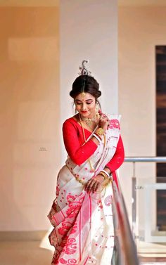 a woman in a red and white sari is standing on the stairs with her arms crossed