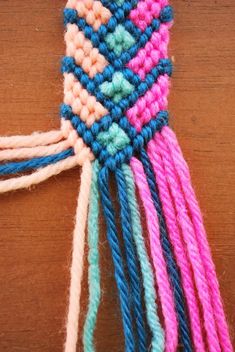 a close up of a piece of yarn on a wooden table with multicolored threads