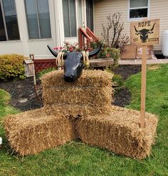 a fake cow head sitting on top of hay bales in front of a house