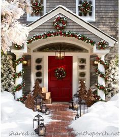 a red door is decorated with christmas wreaths and lights in front of a house