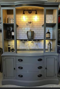 a gray china cabinet with glass doors and shelves on both sides, filled with wine glasses