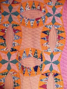 an orange and pink quilt with many designs on it