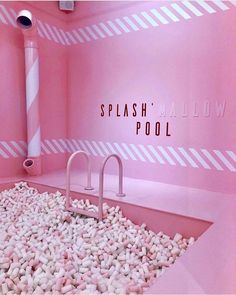 there is a pink bathroom with white rocks on the floor and a pool in the middle