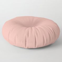 a pink round pillow sitting on top of a white floor