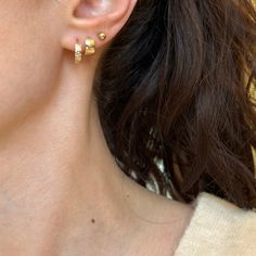 14KT yellow gold hinged, round huggie hoop earrings with scattered cubic zirconia stones. Shown in first ear hole of model. Length: 12.1mm Width: 12.6mm Thickness: 3.3mm Weight: 1.31 grams Stamped 14K Solid 14K gold Huggies/Hoop style as they "hug" the earlobe. Pierced Yellow Gold Cubic Zirconia Huggie Earrings, Gold Plated Huggie Piercings, Gold Plated Round Huggie Earrings With Lever Back, Gold Huggie Piercings For Anniversary, Gold Huggies, Saint Jewelry, Of Model, New Launch, Huggie Hoop Earrings