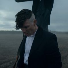 a man in a suit and tie looking at his cell phone while standing next to a cross