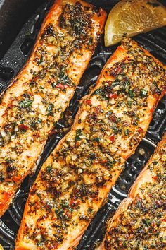 grilled salmon fillets with herbs and lemons on a griddle in a cast iron skillet