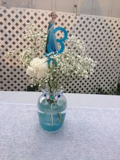 a vase filled with flowers on top of a blue tablecloth covered table next to a fence