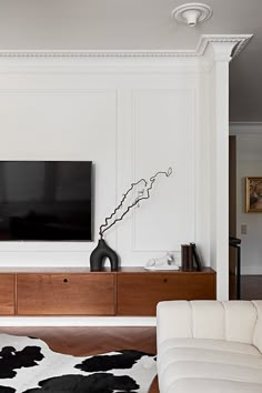 a flat screen tv mounted to the side of a white wall in a living room