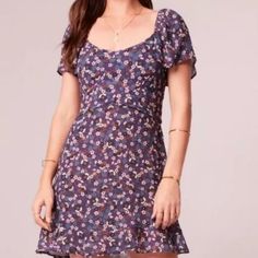 a woman is wearing a dress with flowers on it and she has her hands in her pockets