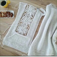 a table topped with white crochet next to a bowl of nuts and a cup of coffee