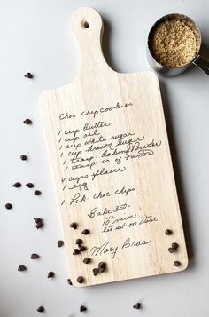 a wooden cutting board with writing on it next to a measuring spoon and chocolate chips