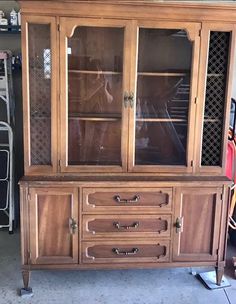 a wooden china cabinet with glass doors and drawers