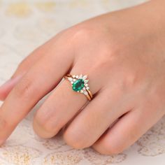 a woman's hand with an emerald and diamond ring