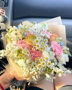 a woman is holding a bouquet of flowers in her hand while sitting in the car