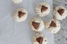 cookies with chocolate triangles on them sitting on a piece of parchment paper