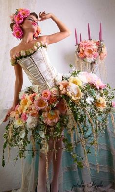 a woman in a corset with flowers on her head and candles behind her