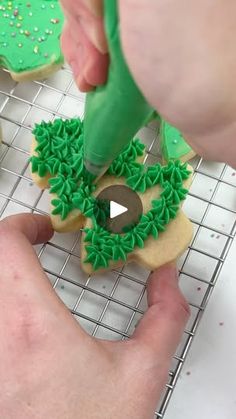 someone is decorating cookies with green icing