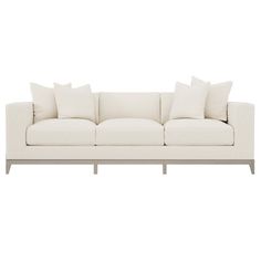 a white couch with four pillows on it and two side tables in front of it