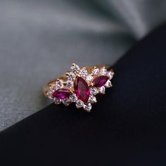 a diamond and ruby ring sitting on top of a black cloth