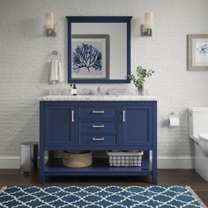 a bathroom with a blue vanity and white brick wall, along with a rug on the floor