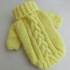 a yellow knitted sweater with a knot on the front and back side, laying on a white surface