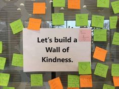 a bulletin board with post it notes attached to it and the words let's build a wall of kindness