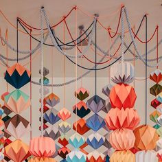 many different colored paper lanterns hanging from strings