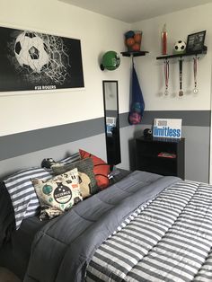 a bed room with a neatly made bed and soccer themed wall hangings on the walls