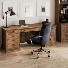 an office desk with a laptop computer on top of it next to a book shelf