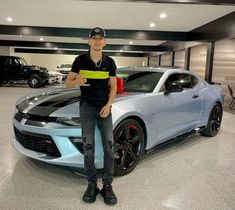 a man standing next to a car in a garage