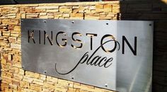 a metal sign that reads kingston place on the side of a brick wall with black lettering