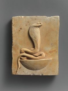 a stone plaque with a snake on it's head in the shape of a bowl