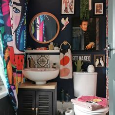 a bathroom with pictures on the wall and a toilet in front of it, next to a sink